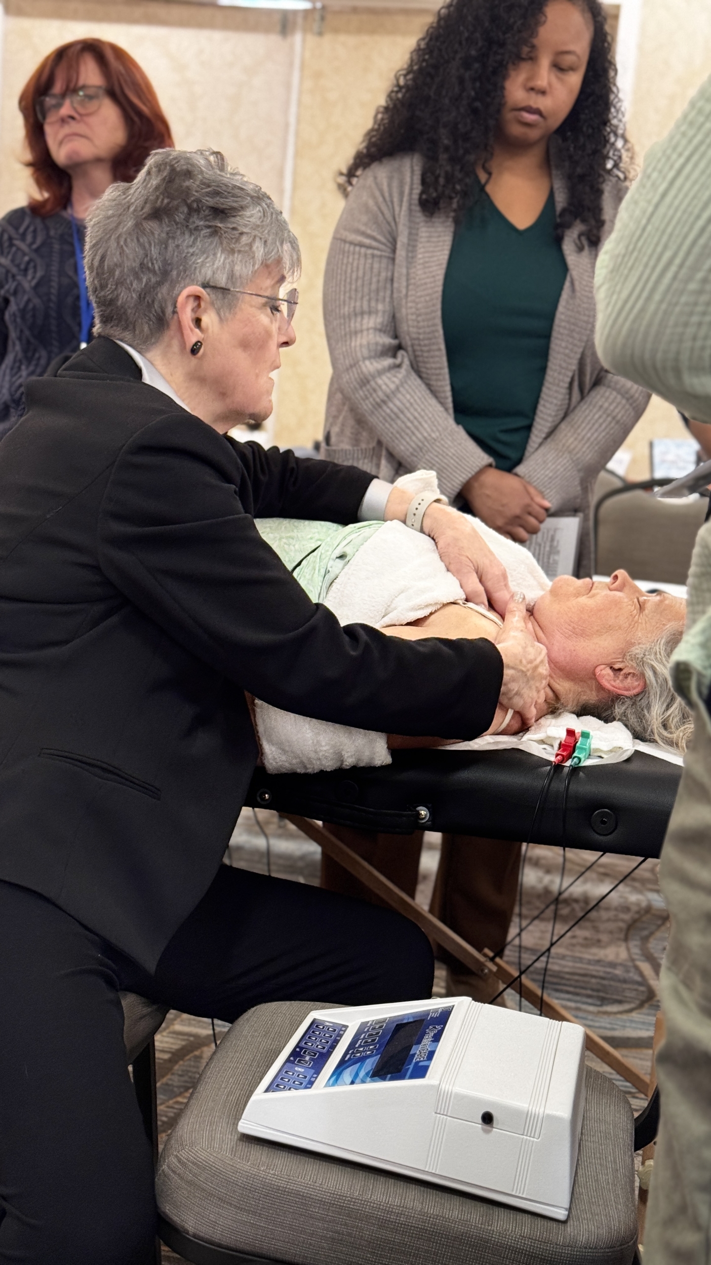 Dr. McMakin performing cervical spine treatment with microcurrent device visible
